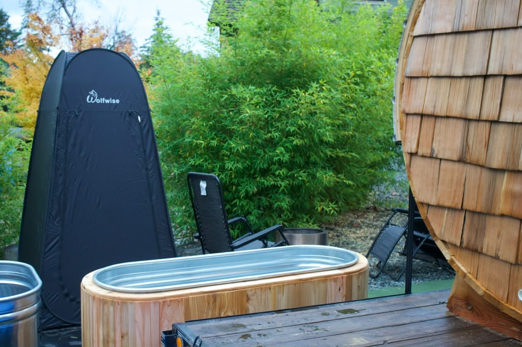 A cedar-clad plunge tub beside the barrel sauna